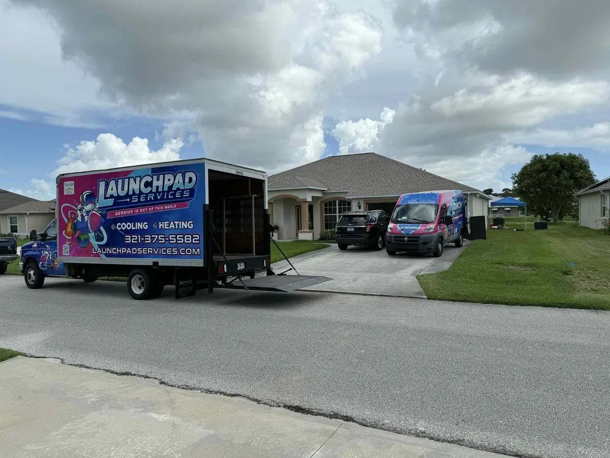 Launchpad Services branded box truck and van at an installation job site