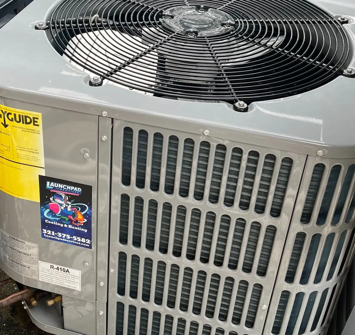 Close-up of a freshly installed AC condenser with a Launchpad Services sticker