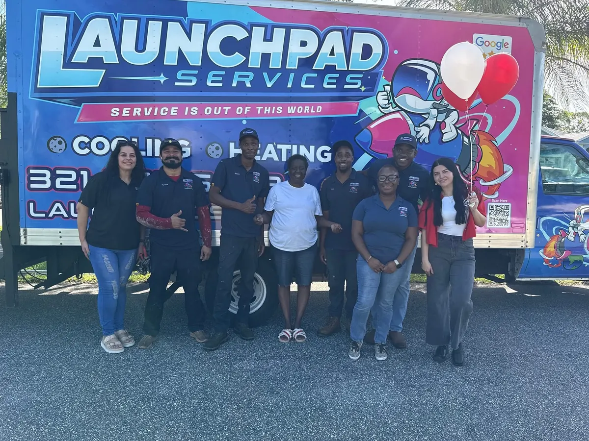 The Launchpad Services team standing together in front of a branded box truck